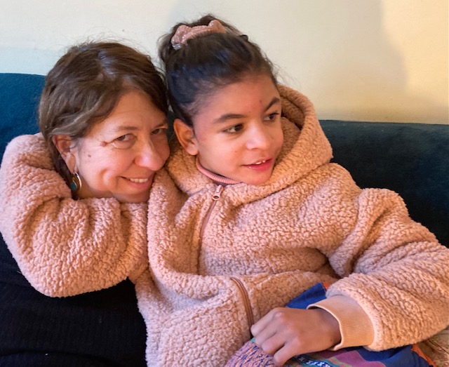 A mum and her daughter hugging on the sofa, smiling.