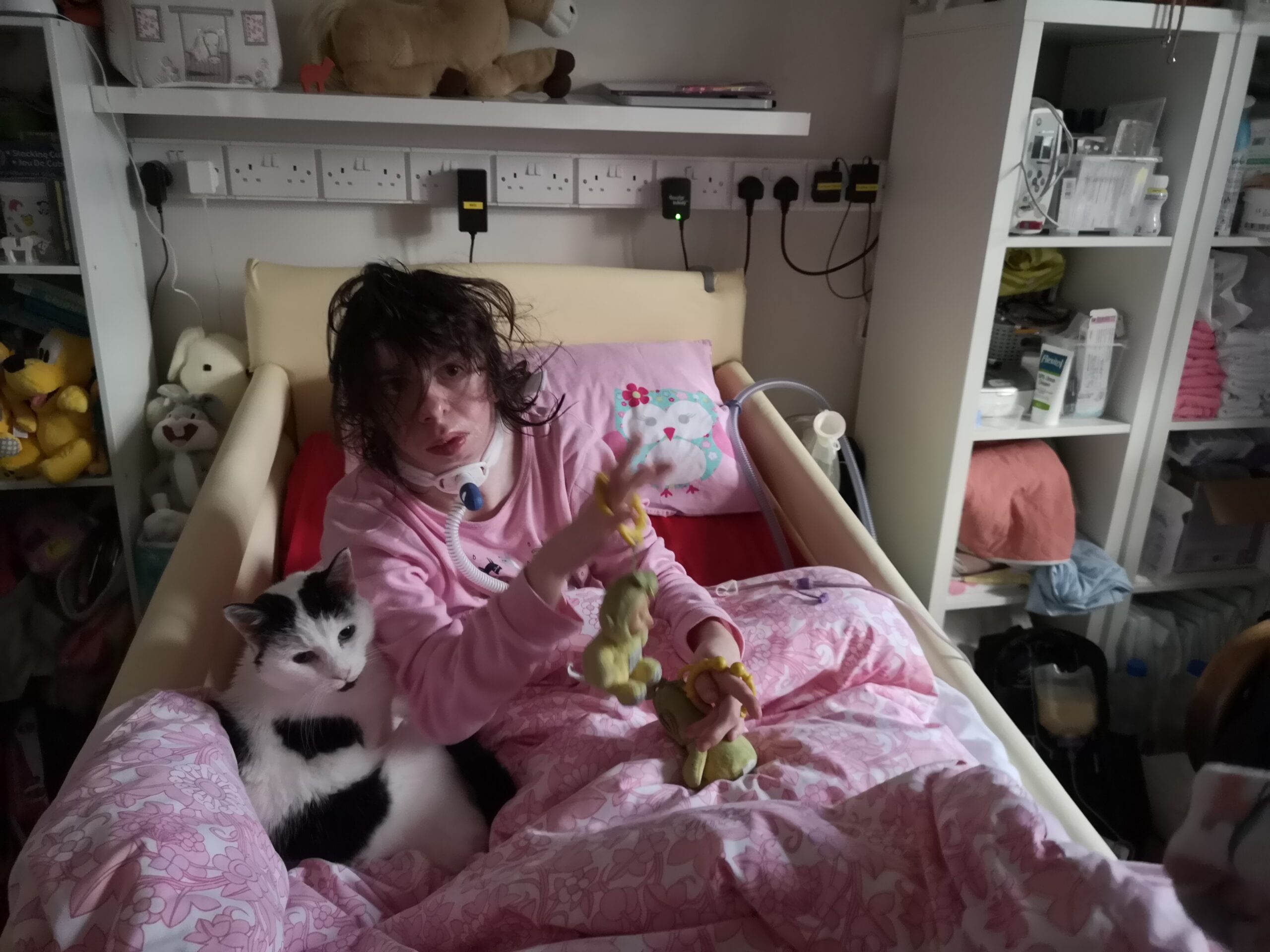 A young woman in bed with her cat, pointing at the camera .